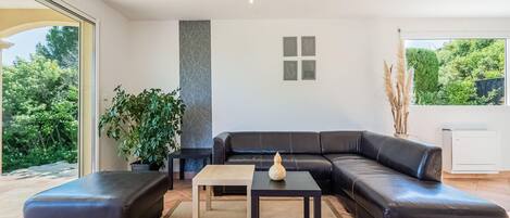 A modern living room with a black leather sectional sofa, a small table, and a potted plant.