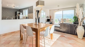 A modern kitchen with a dining area, large windows, and a view of the outdoors. - Charming Villa Near Les Vans (Les Vans)