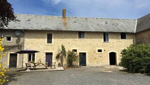 Un bâtiment en pierre de deux étages, doté d’une cour recouverte de gravier, d’une table de pique-nique et d’une antenne parabolique.