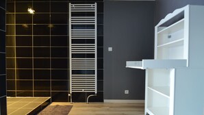 Une salle de bain moderne avec une baignoire blanche, un porte-serviettes et une étagère intégrée.