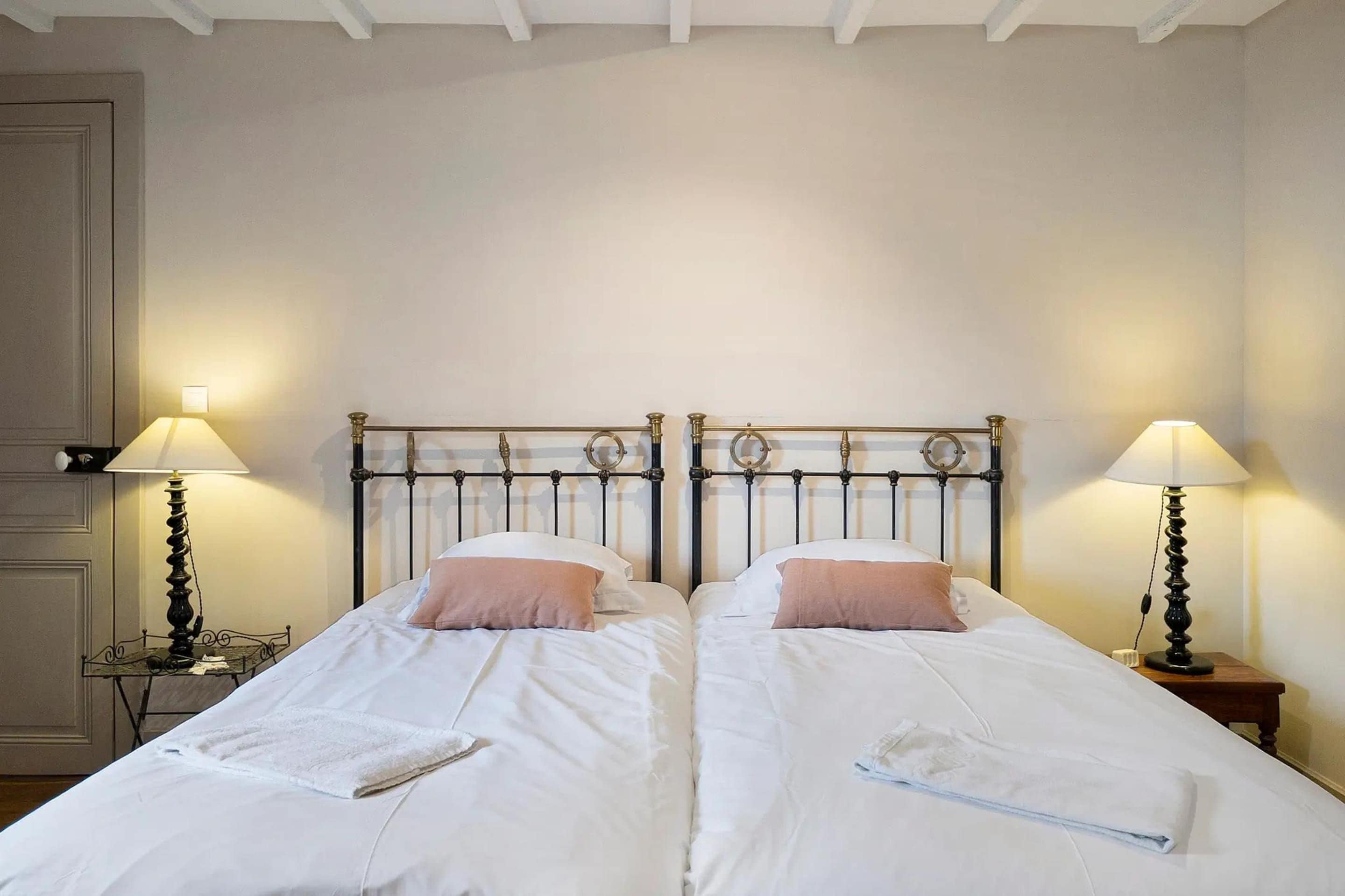A double bed with a metal headboard, two bedside tables with lamps, and a white wall.