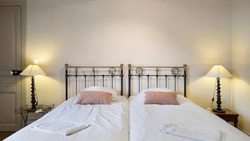 A double bed with a metal headboard, two bedside tables with lamps, and a white wall.