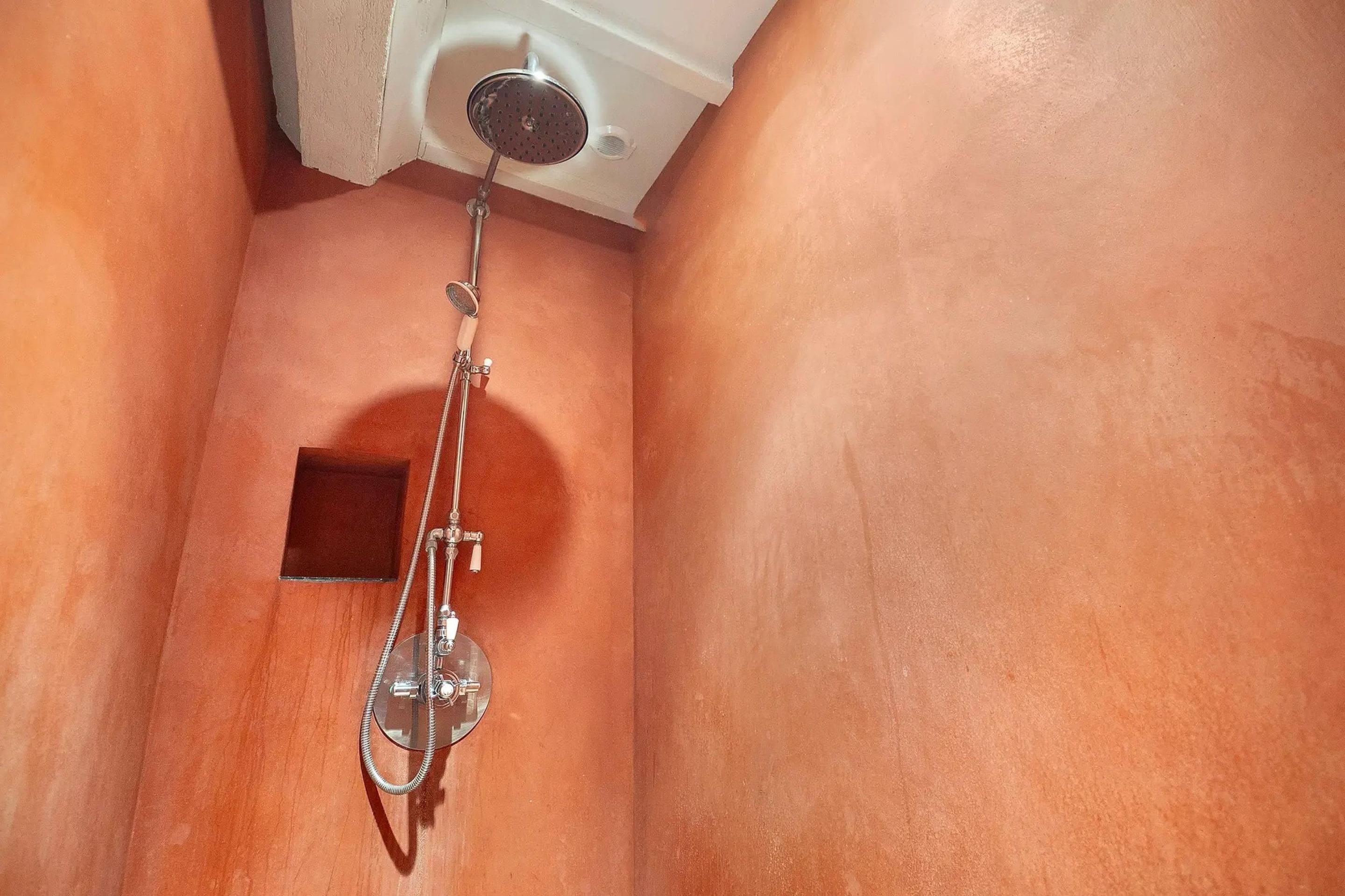 A shower with a handheld showerhead and a wall-mounted faucet.