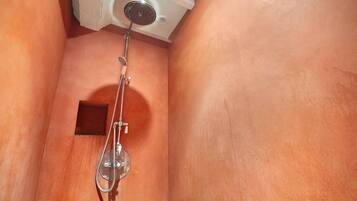 A shower with a handheld showerhead and a wall-mounted faucet.