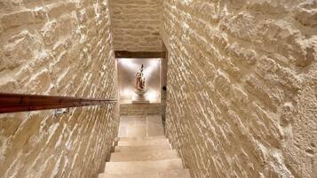 A stone staircase leading to a statue in a narrow corridor.