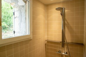Een badkamer met douche, raam en betegelde wanden.