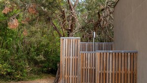 A wooden fence with vertical slats, a concrete pathway, and a natural backdrop of trees and shrubs. - Villa Near Les Vans With Private Pool (Les Salelles)