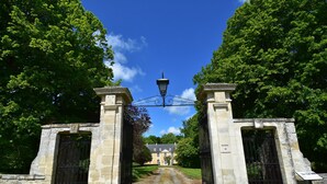 Ein historisches Gebäude mit befestigtem Eingang, einem schmiedeeisernen Tor und blauem Himmel.
