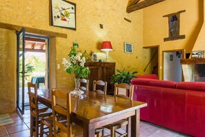 A dining area with a wooden table and chairs, a red sofa, and a red lamp. - Poolside Haven in Salles (Salles-de-Belvès)