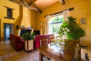 A dining area with a wooden table, red leather seating, and a large window with curtains. - Poolside Haven in Salles (Salles-de-Belvès)