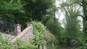A stone staircase leading up to a stone wall with a metal fence on the left. - Charming Brittany Hideaway (Yvias)