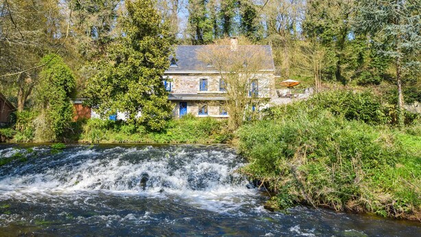 A stone house with a waterfall in front, surrounded by trees. - Charming Brittany Hideaway (Yvias)