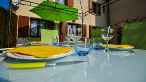 A table set outdoors with a green umbrella, clear glassware, and yellow napkins. - House in Perigord Near Medieval Villages (Prats-du-Perigord)