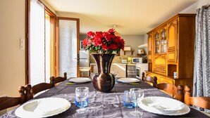 A dining table set with plates, glasses, and a vase of flowers. - House in Perigord Near Medieval Villages (Prats-du-Perigord)