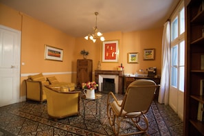 A living room with patterned flooring, a fireplace, and a bookshelf. - Old Wine Storehouse With Terrace and Garden (Thezan-les-Beziers)