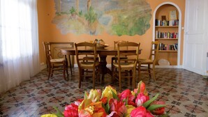 Un coin repas agrémenté d’une fresque murale, d’une bibliothèque et d’un arrangement floral.