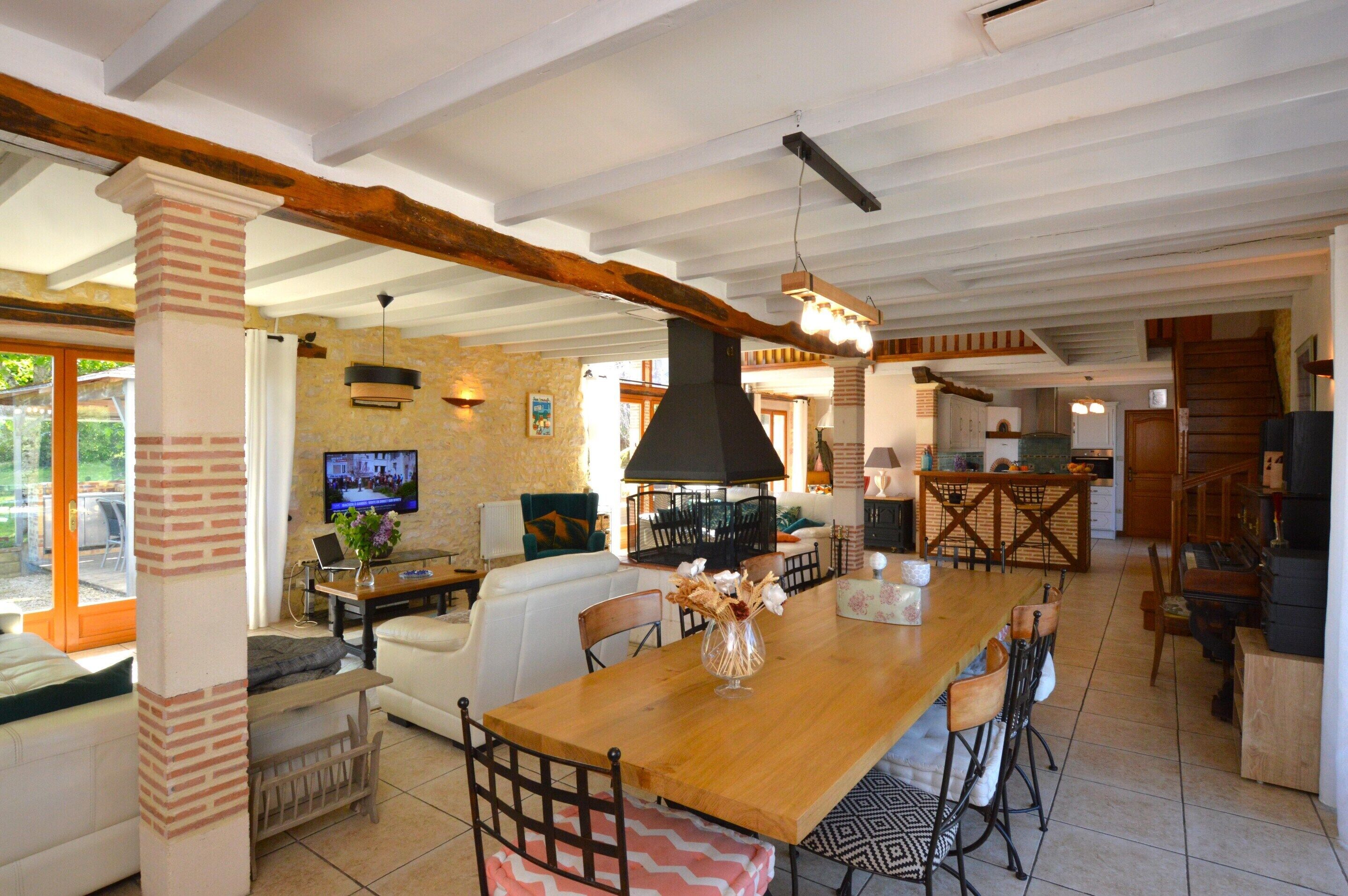 A spacious living area with a wooden dining table, comfortable seating, a TV, and a fireplace.
