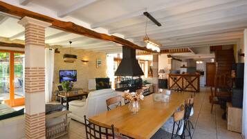 A spacious living area with a wooden dining table, comfortable seating, a TV, and a fireplace.