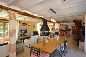 A spacious living area with a wooden dining table, comfortable seating, a TV, and a fireplace.