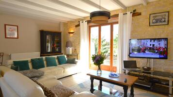 A living room with a sofa, a coffee table, a TV, and a stone wall.