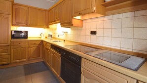 A kitchen with wooden cabinets, a microwave, a stove, and a sink. - Lovely Modern Apartment, Near the Mosel, Shops and Restaurants (Zell (Mosel))