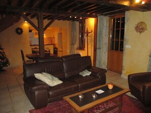A living room with a brown leather sofa, a wooden coffee table with candles, and a Christmas tree. - Holiday Home in Isenay Near Lake and Forest (Isenay)