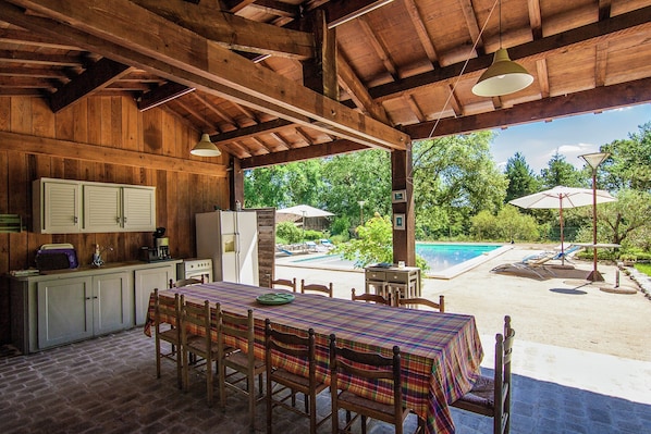 A wooden interior with a dining table, chairs, and a view of an outdoor swimming pool.