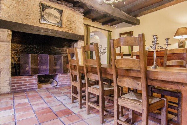 A dining area with wooden chairs, a brick fireplace, and a tiled floor. - Mansion in Bourgnac With Garden (Bourgnac)