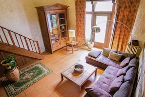 A living room with a sofa, a cabinet, a lamp, and a staircase.