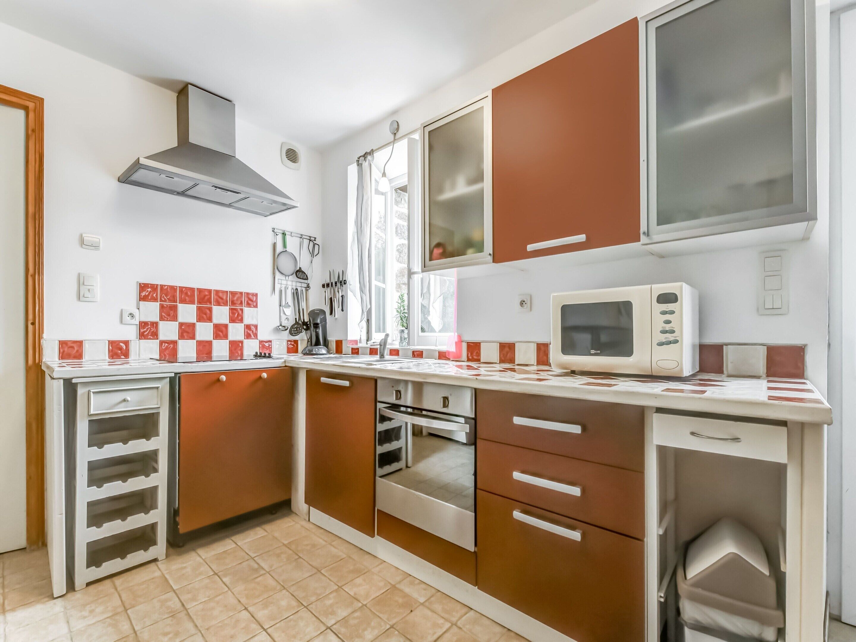 A compact kitchen with a microwave, oven, and stainless steel range hood.