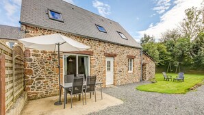 Een stenen huis met een terras, een schommel en een grindpad.