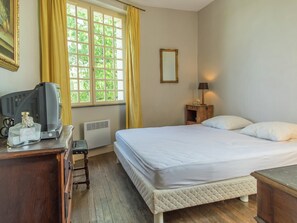 A hotel room with a bed, a desk with a television, a lamp, and a window with curtains. - Riverside Hideaway in Cinais (Cinais)