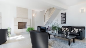 A modern living room with a fireplace, a staircase, a black leather sofa, and a coffee table. - Retreat in Beaumont-en-veron (Beaumont-en-Veron)