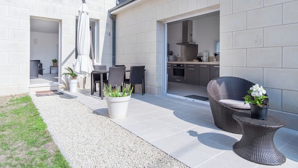 A modern house with a patio area, outdoor furniture, and a kitchen visible through an open door. - Retreat in Beaumont-en-veron (Beaumont-en-Veron)