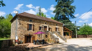 A stone building with a tiled roof, outdoor seating, and a staircase leading to an upper level. - Blanquefort Hill Retreat (Blanquefort-sur-Briolance)