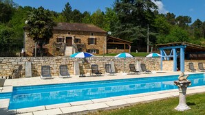 A stone building with a pool, lounge chairs, and umbrellas. - Blanquefort Hill Retreat (Blanquefort-sur-Briolance)