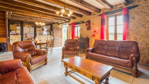 A rustic interior with wooden beams, leather sofas, a wooden coffee table, and a stone wall. - Blanquefort Hill Retreat (Blanquefort-sur-Briolance)