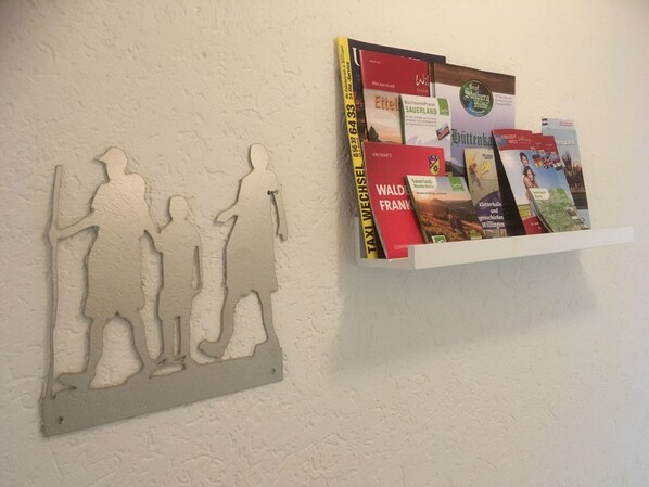 A wall with a relief sculpture of three figures and a white shelf with travel books. - Apartment Near the ski Area (Medebach)