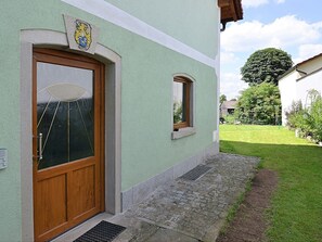 Ein Gebäude mit grüner Fassade, einer Holztür und einem kleinen Fenster.