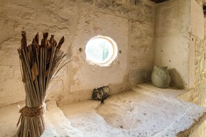 A rustic interior with a woven basket, a small circular window, and a stone wall. - Slate-roofed Hideaway (Cressensac-Sarrazac)