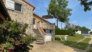 A stone building with a balcony, a staircase, and a covered outdoor seating area. - Saint-beauzire Holiday Home Near Pauillac Castle (Saint-Beauzire)