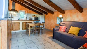 A kitchen with wooden beams, a dining table, and a sofa with cushions. - Saint-beauzire Holiday Home Near Pauillac Castle (Saint-Beauzire)