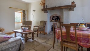 A cozy living room with a fireplace, wooden furniture, and a dining area. - Cottage in an old Remote Farmhouse (Giroux)