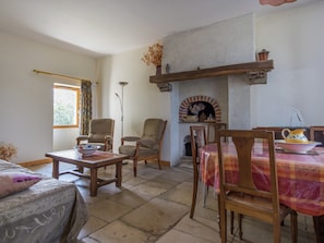 A cozy living room with a fireplace, wooden furniture, and a dining area.