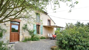 A rustic stone house with a wooden door, a brick window, and a covered outdoor seating area. - Cottage in an old Remote Farmhouse (Giroux)