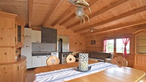 En stuga med träpanel på insidan, innehållande ett kök, en matplats och en soffa.