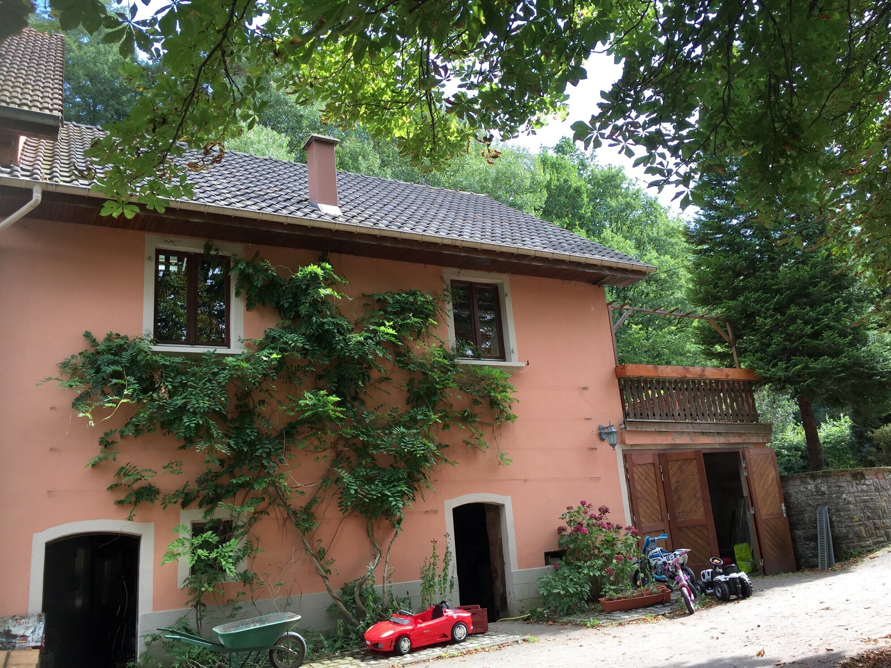 Uma casa com telhado de telhas, uma garagem e um carrinho de mão.