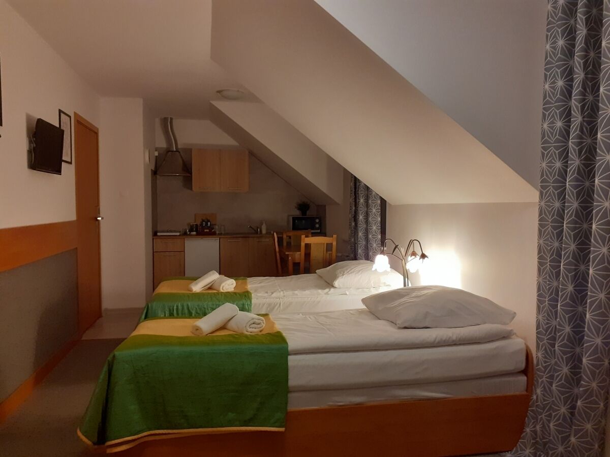 A hotel room with two beds, a kitchenette, and a dining area.