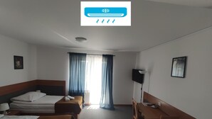 A hotel room with two beds, a desk, a chair, a TV, and a window with curtains. - Hotel Arkadia (Plock)