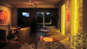 A modern dining area with a TV, comfortable seating, and a view of the outdoors. - Hotel Arkadia (Plock)